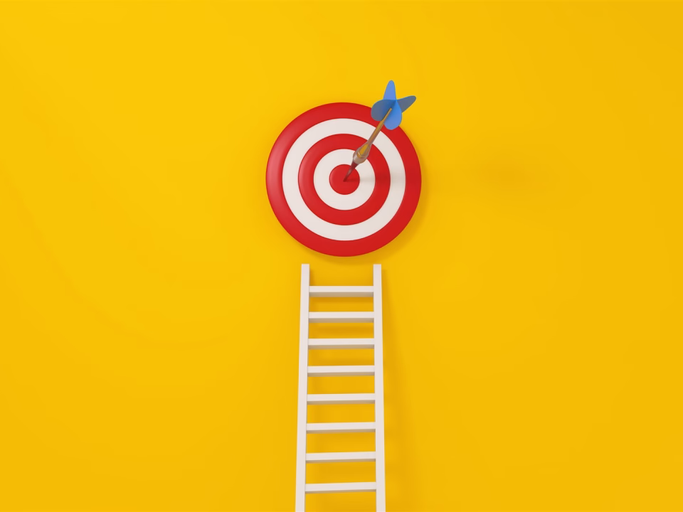 A dart in the centre of a target at the top of a ladder
